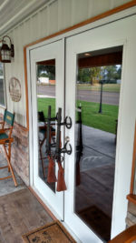 Photo of exterior doors to MWA lodge, outfitted with rifles for door handles