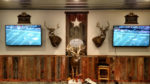 Photo of buck centerpiece flanked by two flatscreens displaying a football game